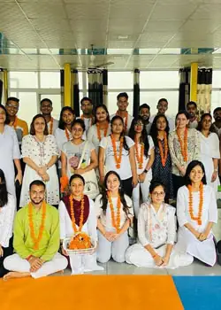 Students and teachers in a group photo wearing flower garlands in the yoga hall
